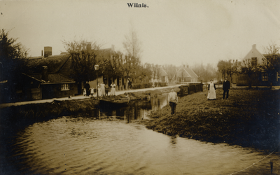 15333 Gezicht in de Herenweg (?) met wetering, bebouwing en beplanting te Wilnis uit het westen; met enkele personen.  ...